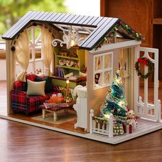 a doll house with furniture and christmas decorations on the outside, including a tree in the living room