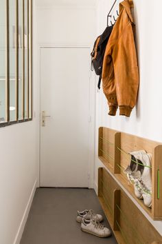 a pair of shoes sitting on the floor in front of a wall mounted coat rack