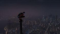 a man standing on top of a tall pole in the middle of a city at night