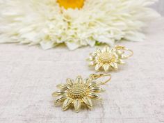 "These are lovely and beautiful shinning golden plated sunflower earrings. They hang underneath golden plated French ear wires. The earrings measure about 37mm (1.5 inches) long from the top of the earwires to the bottom of the flower. A wonderful idea for gift giving or as a little treat for yourself. Your item will arrive in gift wrap and ready to gift. Measurements and details: Total length: approximately37mm (1.5\") Flower: 24mm across Ear wire: golden plated French ear wires PLEASE NOTE: Al Emerald Green Earrings, Sunflower Jewelry, Sunflower Earrings, Flower Hair Comb, Daisy Earrings, Sunflower Wedding, Knot Earrings, Flower Jewelry, Crystal Drop Earrings