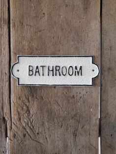 a bathroom sign on the side of a wooden door that says, bath room with black and white lettering