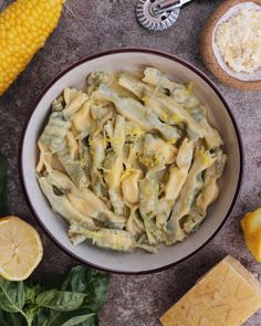 a bowl filled with pasta and cheese next to corn on the cob, butter, and seasoning