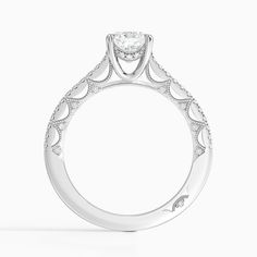 a white gold engagement ring with an intricate design on the band and round brilliant cut diamond center