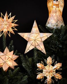 christmas lights are hanging from a tree with pine cones and star shaped ornaments on it