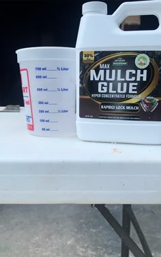 a bottle of mulch glue sitting on top of a table next to a measuring cup