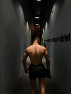 a man walking down a hallway with no shirt on