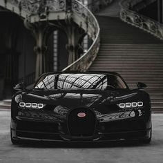 the black bugatti is parked in front of some stairs