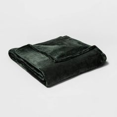 a dark green blanket folded on top of a white surface