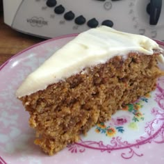 a piece of carrot cake with white frosting on a pink and purple plate next to an oven