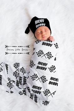 a newborn baby is wrapped in a white blanket and wearing a black hat with arrows