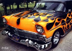 an orange and black car with flames painted on it's front hood, parked in a driveway