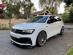 a white volkswagen tiro parked in front of a house with black rims and red brake pads