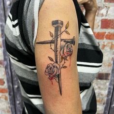 a woman with a cross and roses tattoo on her arm