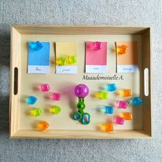 a wooden tray with magnets and paper clips on the bottom, along with colored sticky notes attached to them