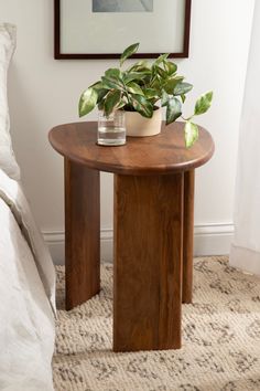 a wooden table with a potted plant sitting on it's side next to a bed