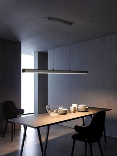 a dining table with two chairs and plates on it in a room that has concrete walls