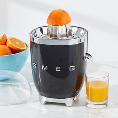 an orange juicer sitting next to a bowl of oranges