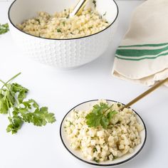 two bowls filled with rice and cilantro garnished with parsley on the side