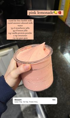 a person holding up a pink lemonade in a plastic cup with text on it