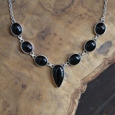 Timeless and beautiful! This 7-stone Black Onyx necklace features beautiful quality, Black Agate pear-shaped central focal pendant, with 3 anchoring ovals elegantly set on either side of the focal, around the neck. Beautifully hand set one by one in .925 Sterling Silver. Romantic. Classic and perfect. A timeless black necklace you will always turn to! Black Agate Pear shape 11X21X6mm 6 Black Agate Ovals 10X12mm .925 Sterling SilverAll Sterling Silver 16-18 inch Length Agate enhances creativity and strengthens the intellect, making it a beneficial stone for both students and artists. It is also known as a good luck stone. As a stone of harmony, one of the things agate does is balance yin/yang energy. All jewelry designs are created using natural gemstones. There will be some natural variati Classic Onyx Necklace With Black Enamel, Classic Oval Onyx Necklaces, Formal Onyx Oval Necklace, Classic Black Oval Pendant Necklace, Formal Black Necklaces With Natural Stones, Elegant Onyx Oval Cabochon Jewelry, Elegant Oval Cabochon Onyx Jewelry, Black Onyx Necklaces With Stones, Black Onyx Necklace With Stones