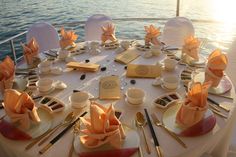 the table is set up for an elegant dinner party on board a yacht in the ocean