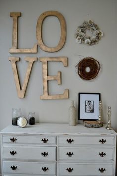 a white dresser sitting in front of a wall with love spelled on the wall above it