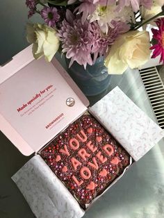 a box that has some kind of cake in it on a table next to flowers