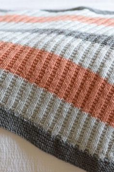 an orange and gray blanket on top of a bed