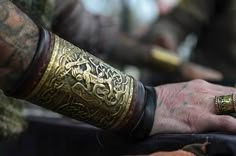 a close up of a person's hands with tattoos and rings on their fingers