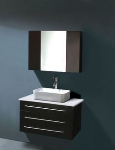 a bathroom sink sitting under a mirror next to a wall mounted faucet and cabinet