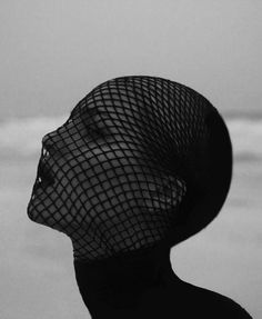 a black and white photo of a woman's head wearing a netted veil