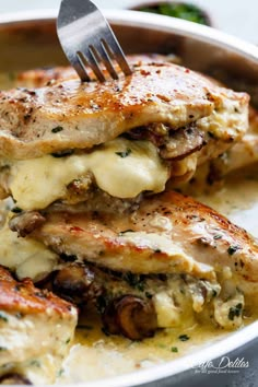 a white plate topped with chicken covered in sauce and cheese, next to a fork