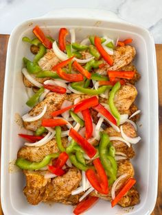 chicken fajita with peppers and onions in a white casserole dish