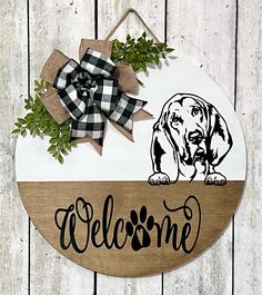 a welcome sign with a dog on it and a bow hanging from the front door