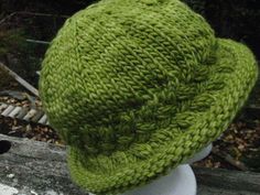 a green knitted hat sitting on top of a white mannequin's head