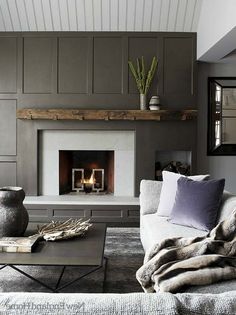 a living room filled with furniture and a fire place in the middle of it's wall