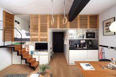 a kitchen and living room with stairs leading up to the top floor in an apartment