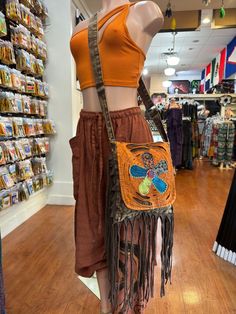 a mannequin wearing a skirt and orange top holding a purse in a store