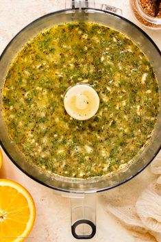 an overhead view of a food processor filled with broth and oranges next to other ingredients