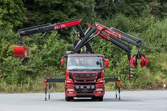 a red truck driving down a road next to trees