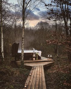 a hot tub sitting on top of a wooden platform in the woods next to trees