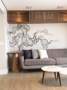 a living room with a gray couch and wooden shelves on the wall, along with a white coffee table