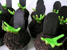 cupcakes decorated with black and green frosting are arranged in the shape of alien hands