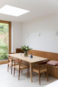 a dining table with four chairs and a bench in front of a large open window