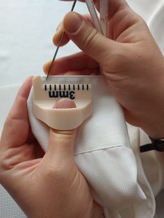 a person is sewing on a white shirt with a pair of scissors in their hand