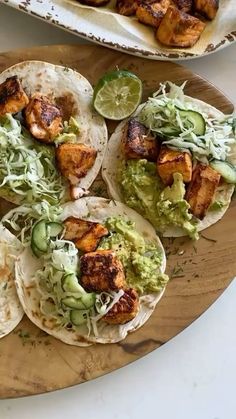 some tacos are sitting on a wooden plate