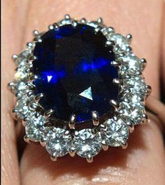 a woman's engagement ring with an oval blue sapphire surrounded by white diamonds