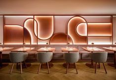 the interior of a restaurant with wooden tables and chairs in front of an illuminated wall