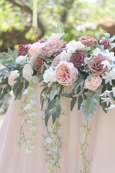 an arrangement of flowers on top of a table with greenery and foliage in the middle