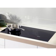 a black stove top sitting on top of a counter next to a pot and pan